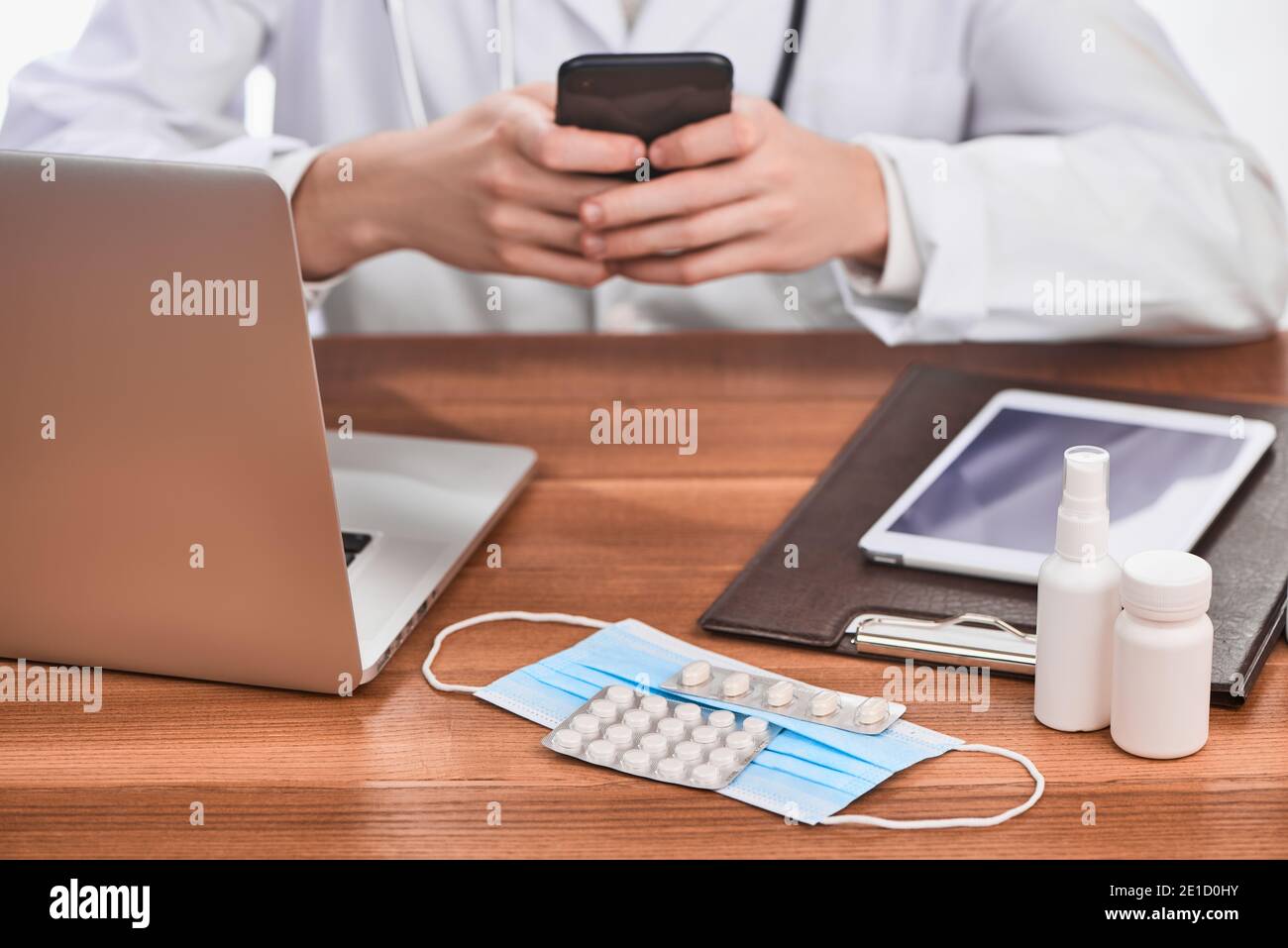 Maschera facciale, pillole, laptop, tablet e appunti con documenti sulla scrivania del medico Foto Stock