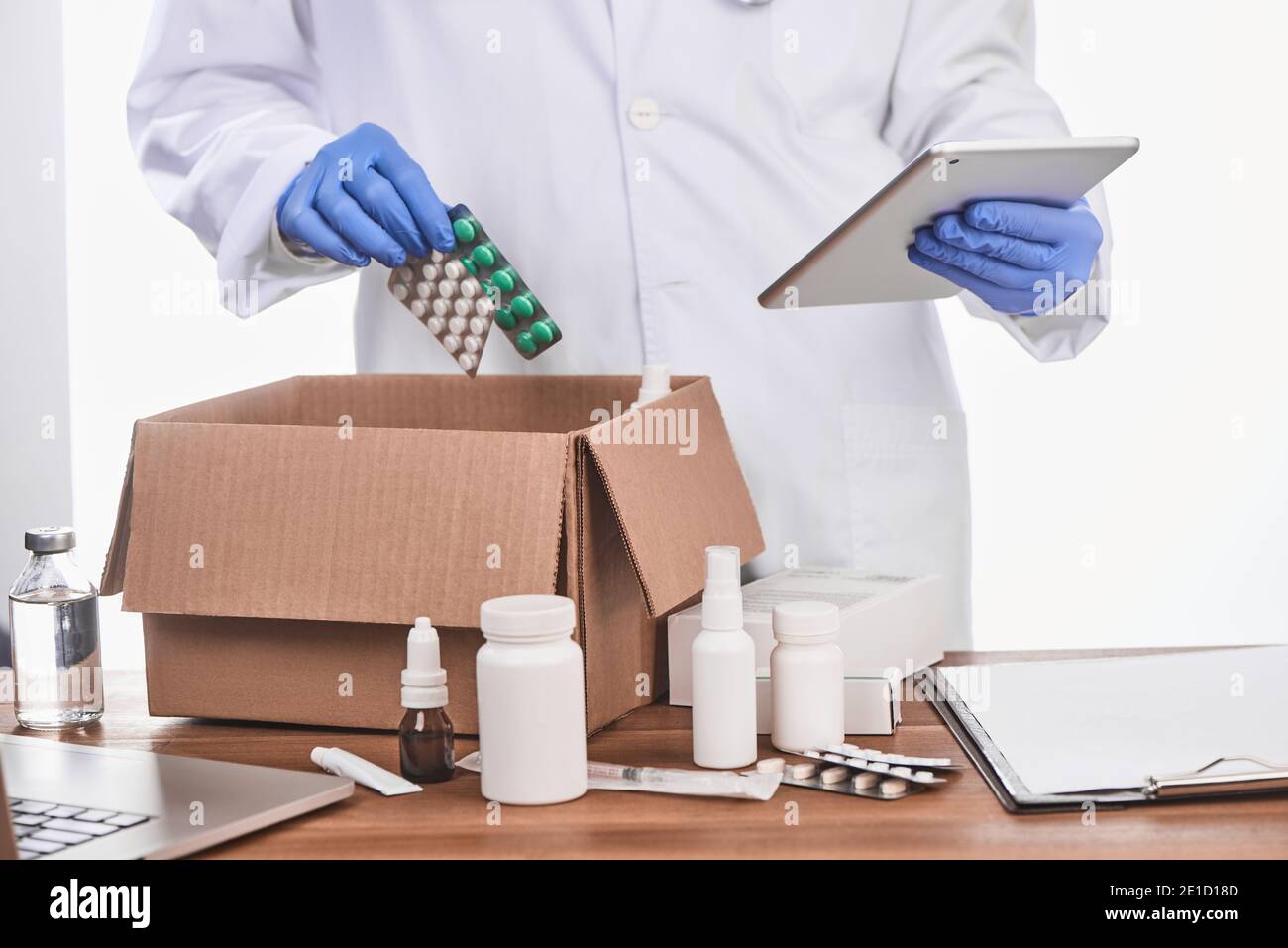 Medico che guarda una diagnosi su una compressa e imballaggio farmaci per un paziente Foto Stock