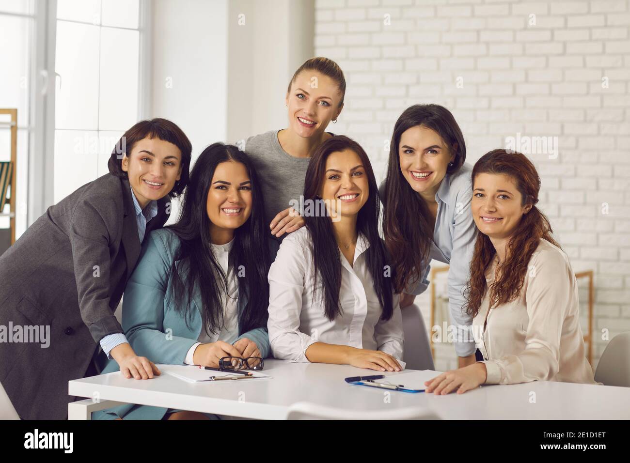 Ritratto di gruppo di giovani donne d'affari felici che sorridono alla macchina fotografica durante la riunione d'ufficio Foto Stock