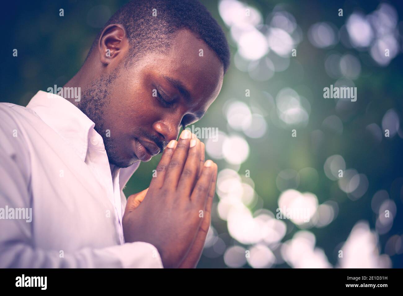 Uomo africano che prega per ringraziare god.Low stile chiave Foto Stock