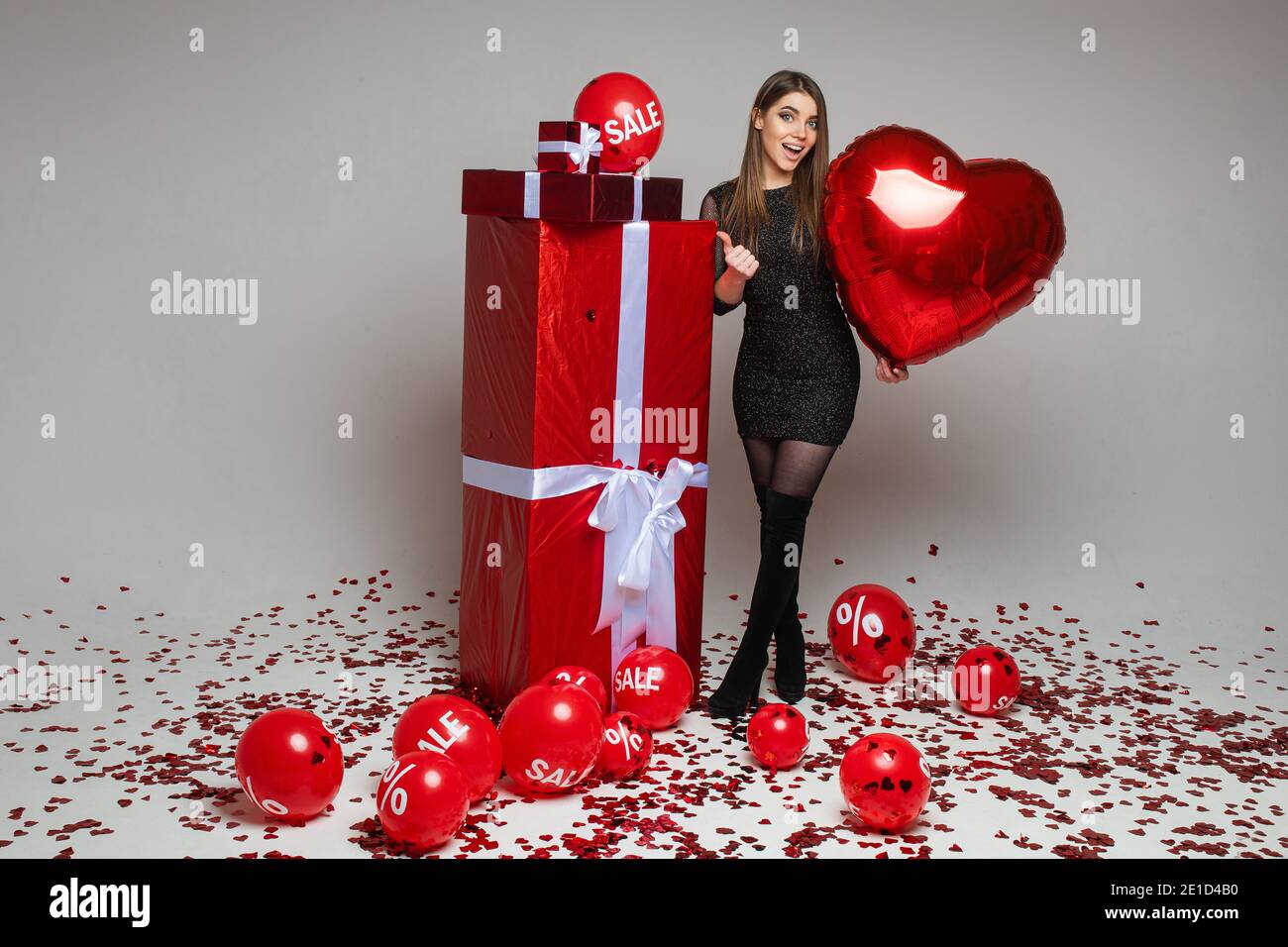 Allegra bruna ragazza in abito che indica i regali. Foto Stock