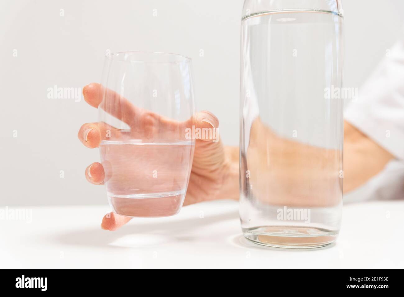 mano che tiene un bicchiere d'acqua Foto Stock