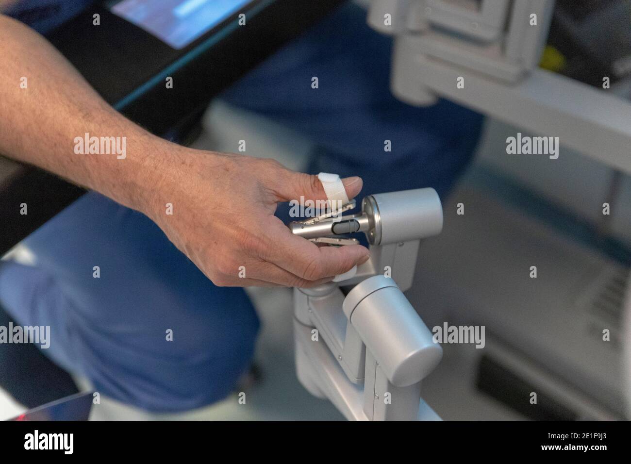 un chirurgo manipola i comandi di un robot che funziona un paziente Foto Stock