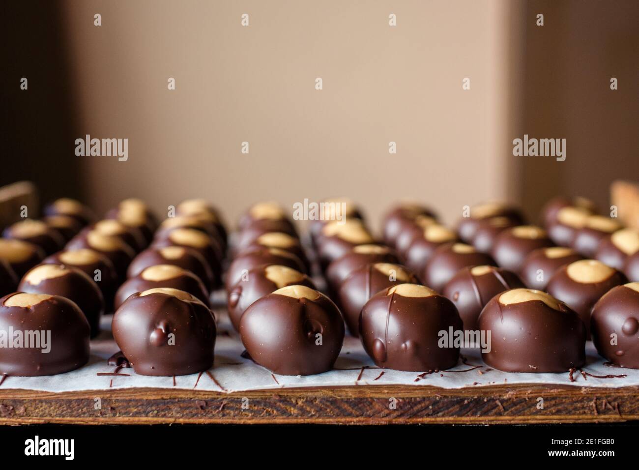 file di caramelle al cioccolato ben allineate si sparse una tavola di legno Foto Stock