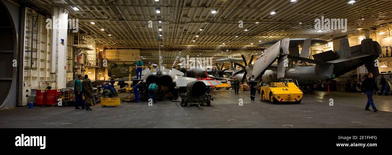 Tecnici che lavorano su un aereo Hawkeye (R) e su aerei da combattimento francesi Rafale (a sinistra e al centro), all'inizio del 22 marzo 2011 a bordo della portaerei francese Charles de Gaulle che ha lasciato il porto meridionale di Tolone due giorni fa per partecipare alle operazioni militari in Libia. Foto di Raphael Martinez/MARINE NATIONALE/ABACAPRESS.COM Foto Stock