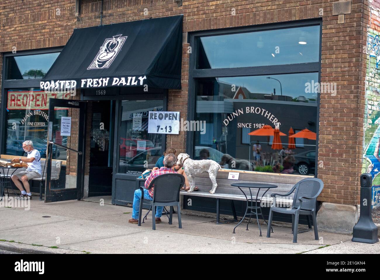 Il Dunn Brothers Coffee Shop mantiene la propria distanza sociale, ma è aperto per il servizio, con posti a sedere all'esterno con un cane doodle d'oro St Paul Minnesota, Stati Uniti d'America Foto Stock