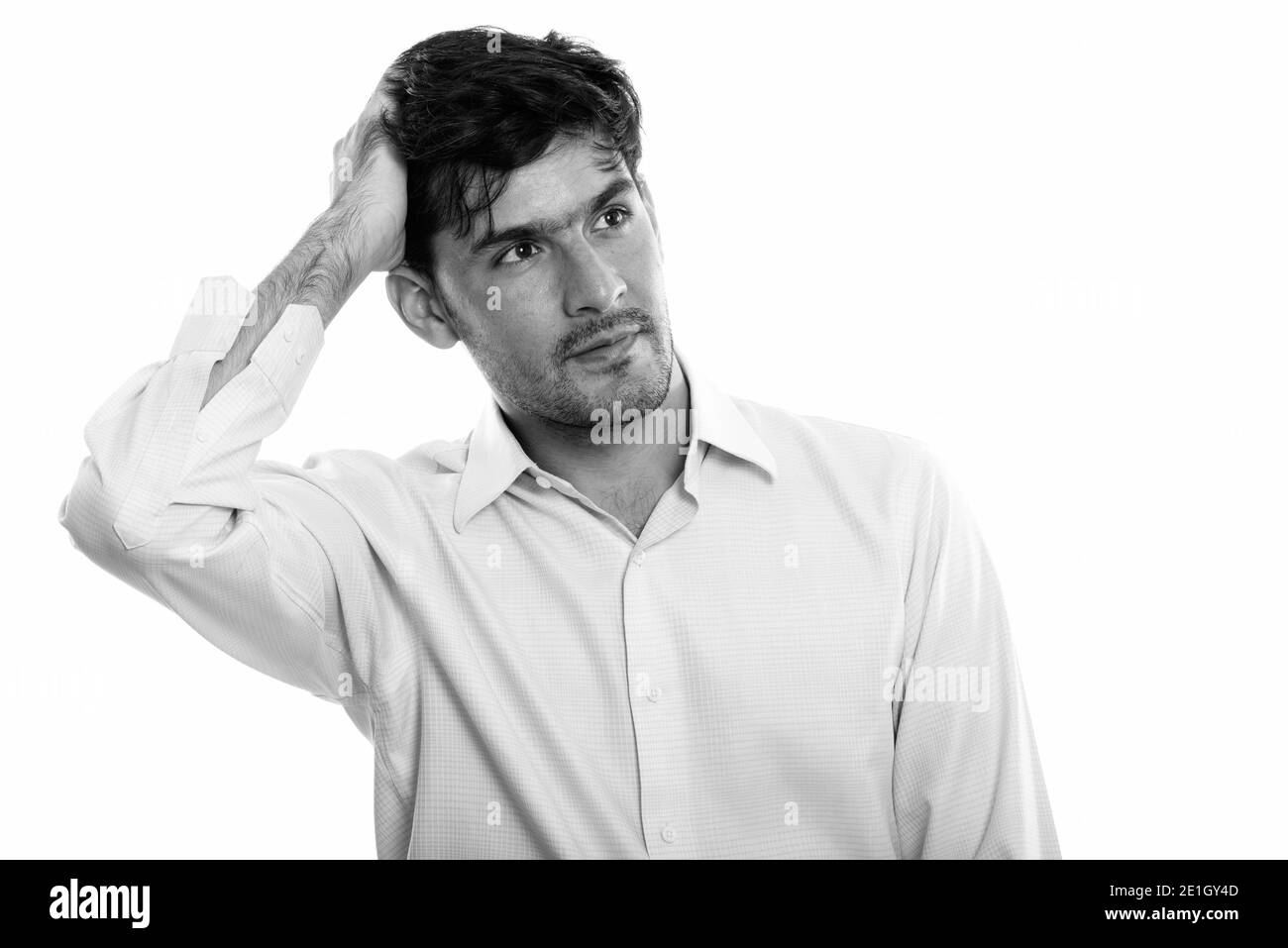 Studio shot del giovane imprenditore persiano pensando mentre i capelli di spazzolatura indietro Foto Stock