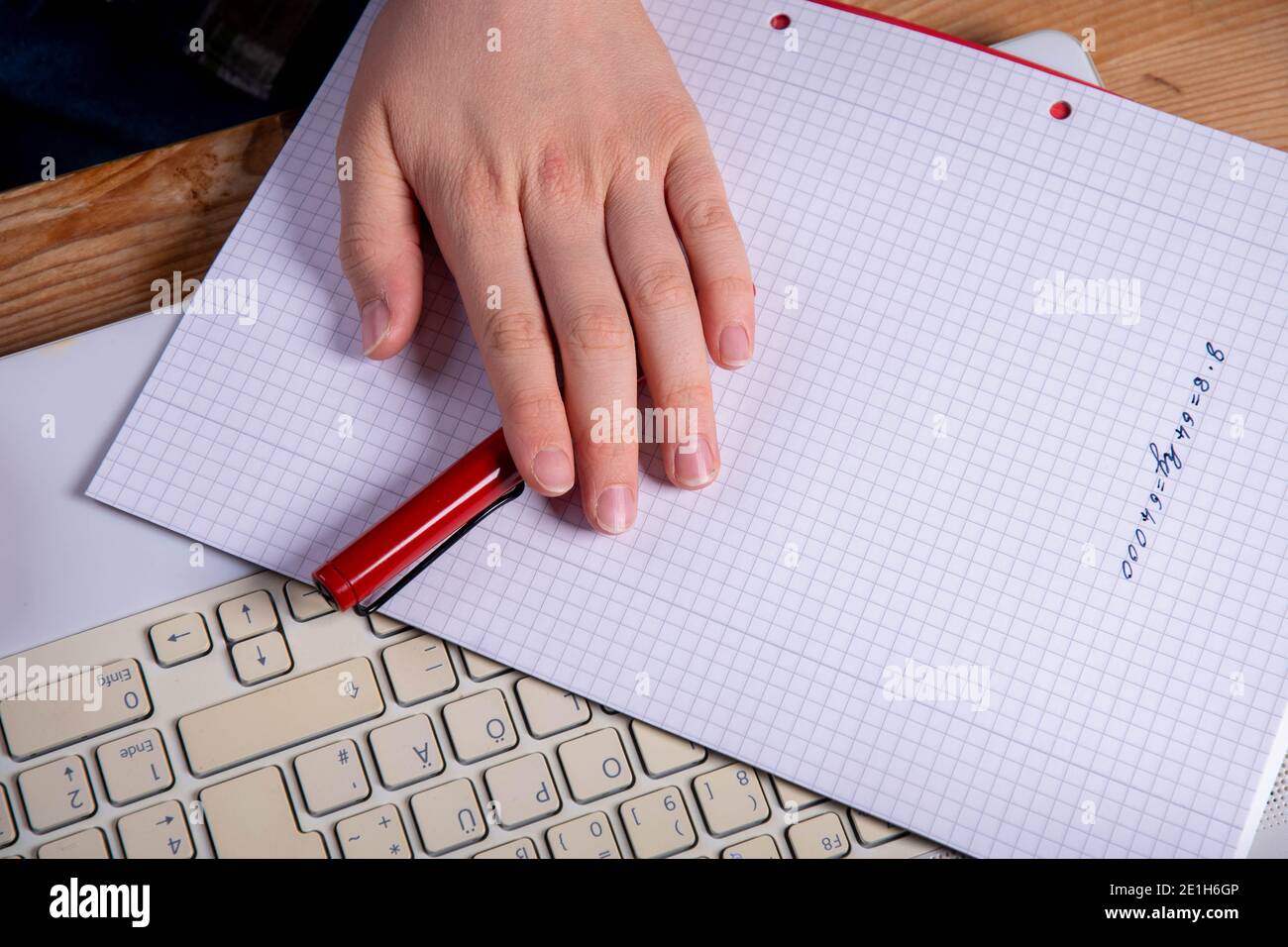 Mano con penna stilografica della tastiera del computer portatile e blocco note vuoto Foto Stock