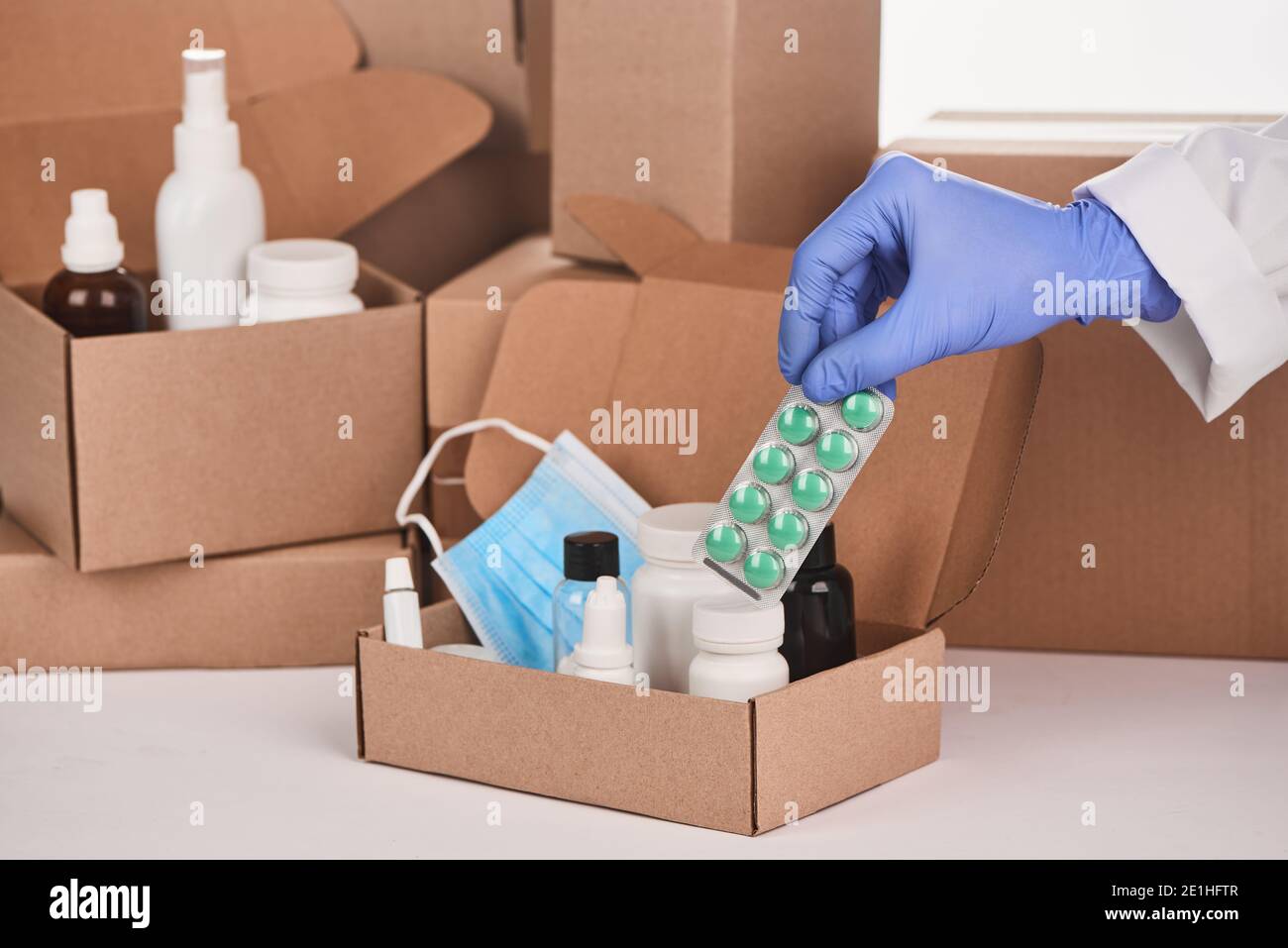 La mano del farmacista in un guanto che mette un blister di pillole in una scatola Foto Stock