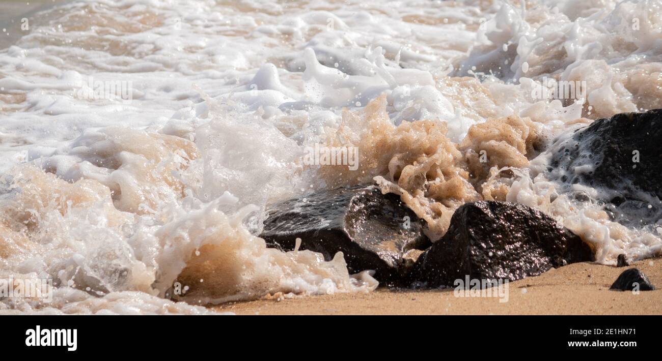 le onde dell'oceano si infrangono sulle rocce sulla spiaggia, l'acqua di mare si rompe in schiuma bianca. Foto Stock