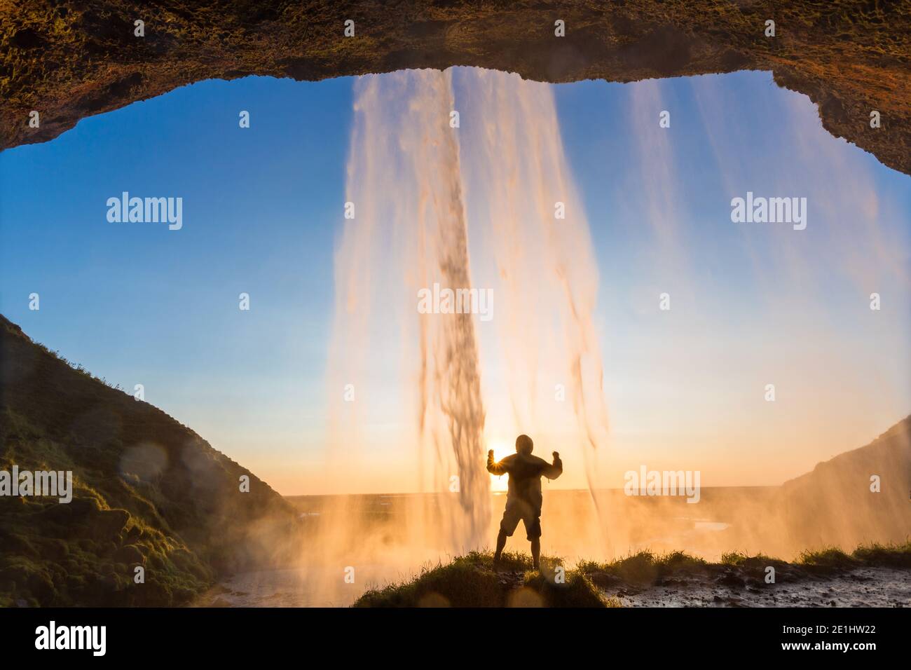 Uomo dietro la cascata Seljalandsfoss, Islanda del Sud, Islanda Foto Stock