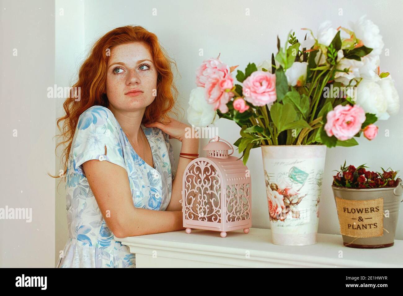 Ritratto di giovane donna rossa con frettole in abito blu in sole primavera giorno a casa. Bellezza naturale. Giorno della donna. Biglietto d'auguri. Foto Stock