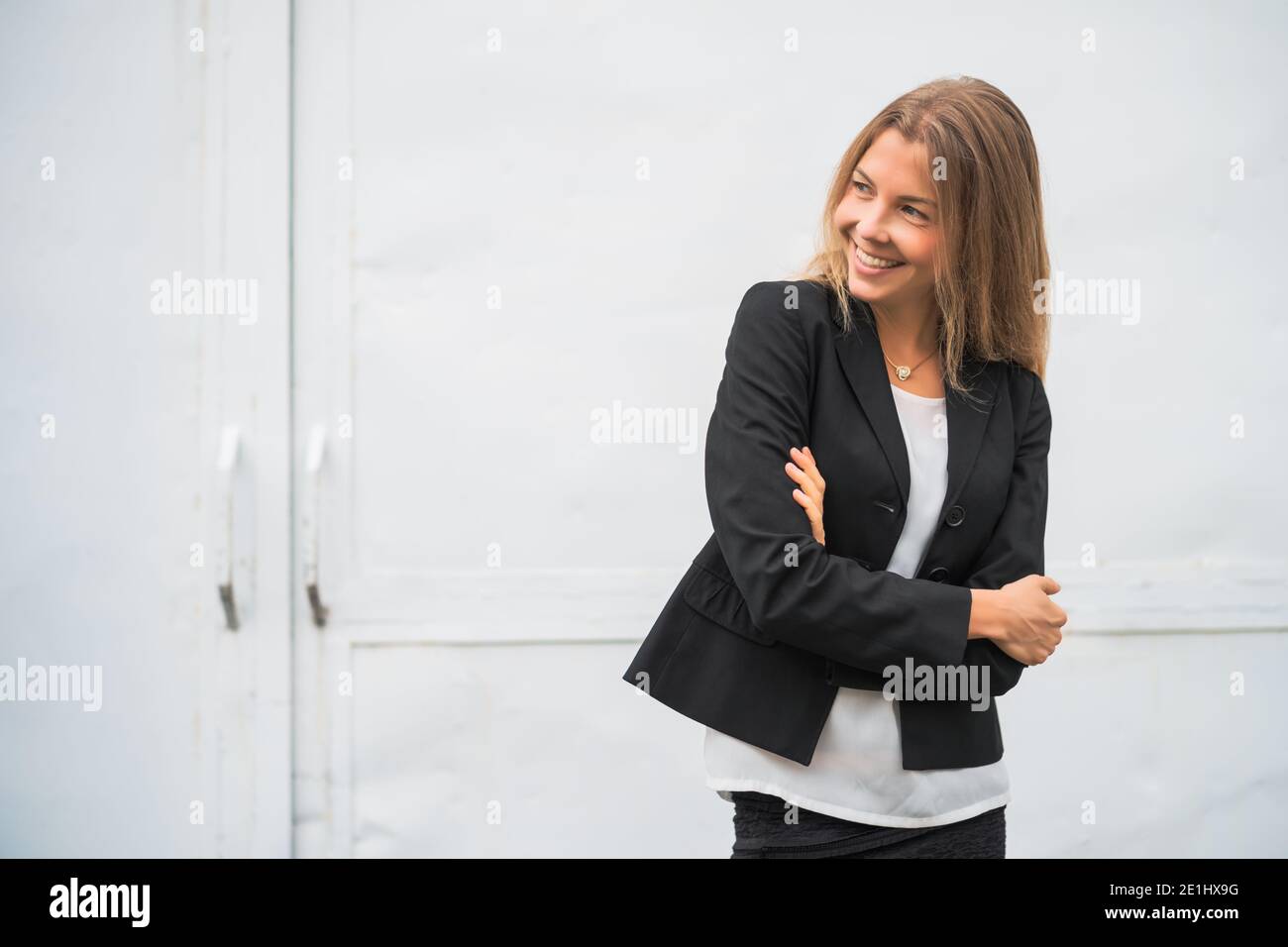 Ritratto esterno di felice donna d'affari moderna. Donna d'affari bionda è in piedi all'aperto e sorridente. Foto Stock