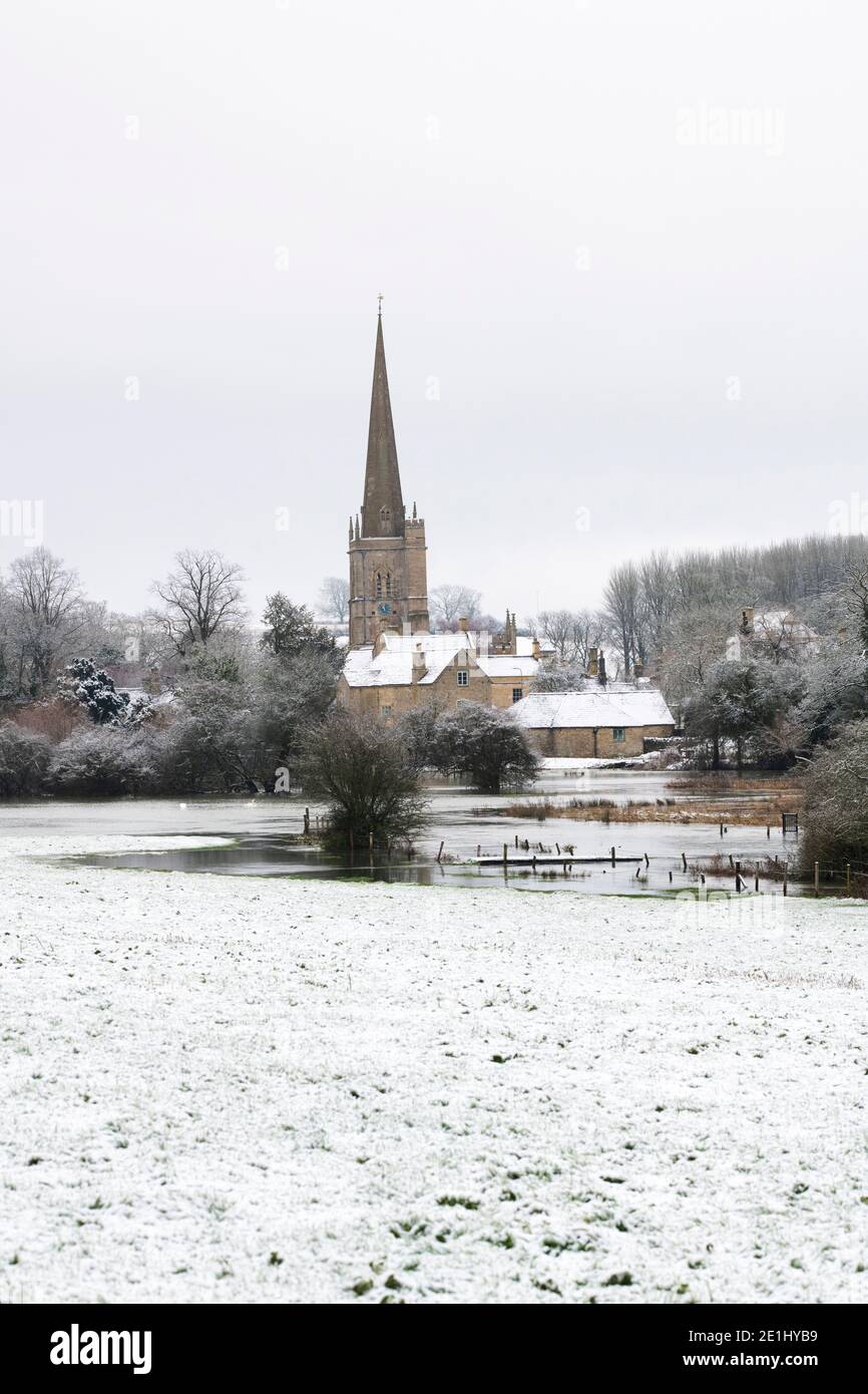 Fiume Windrush allagato e la chiesa di San Giovanni Battista nella neve di dicembre. Burford, Cotswolds, Oxfordshire, Inghilterra Foto Stock