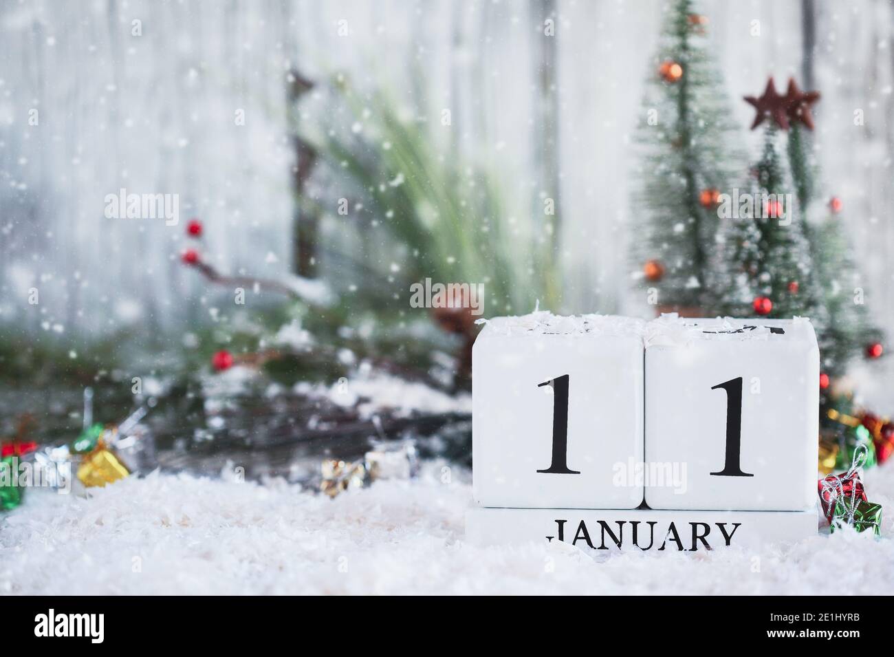 Blocchi calendario in legno bianco con la data 11 gennaio e decorazioni natalizie con neve. Messa a fuoco selettiva con sfondo sfocato. Foto Stock