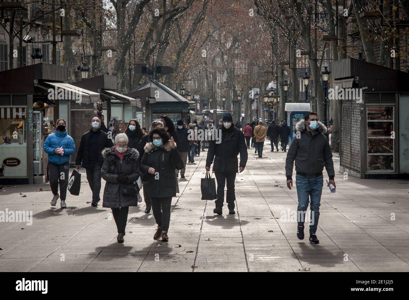 Persone che indossano maschere a piedi lungo la Rambla a Barcellona. Alla fine della stagione natalizia, diverse regioni spagnole hanno inasprito le misure per fermare la diffusione della terza ondata di coronavirus, in quanto la pressione degli ospedali è in aumento. Alcuni studi concludono che il nuovo ceppo di coronavirus, rilevato per la prima volta nel Regno Unito, circola in Spagna da due settimane. Foto Stock