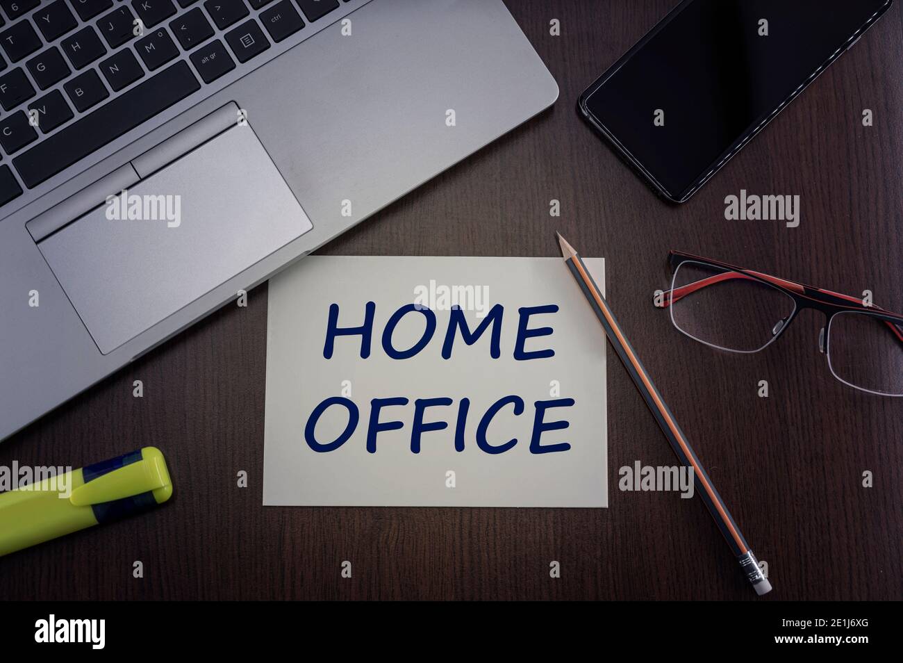 Vista dall'alto di computer portatile, telefono, occhiali e matita con scheda con iscrizione home Office. Foto Stock