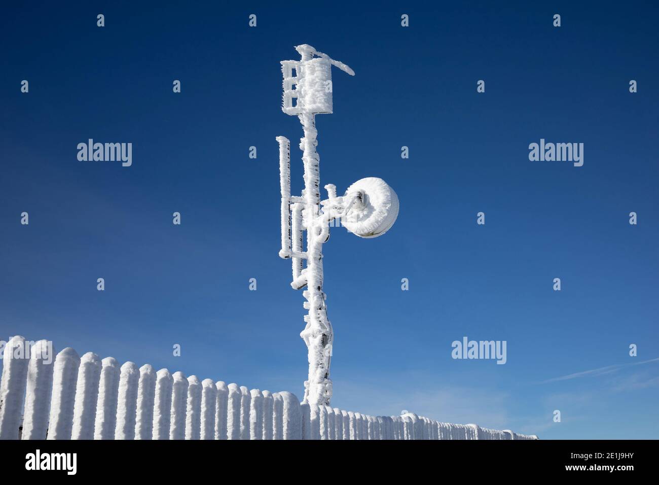Torre meteorologica con apparecchiature di misurazione, antenna satellitare. Il dispositivo è coperto da neve surgelata, ghiaccio e rime in winte freddo e gelo Foto Stock