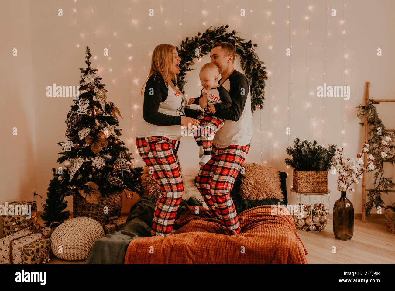 la famiglia felice in pigiama con i genitori bambini gioca con il bambino che salta sul letto in camera da letto. i vestiti di famiglia di nuovo anno sembrano vestiti. San Valentino Celebrate Foto Stock