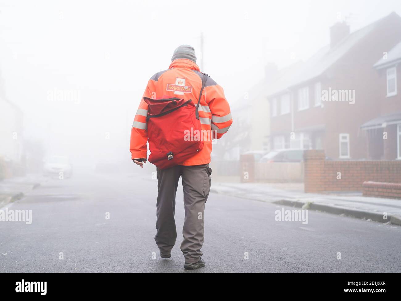 Kidderminster, Regno Unito. 7 gennaio 2021. Tempo in Gran Bretagna: Nebbia pesante e temperature di congelamento sono lenti a salire a Kidderminster. Questo postino cammina con attenzione lungo una strada residenziale nebbiosa, tutte le strade laterali sono ancora ghiacciate e marciapiedi molto scivoloso sotto il piede. Credit: Lee Hudson/Alamy Live News Foto Stock