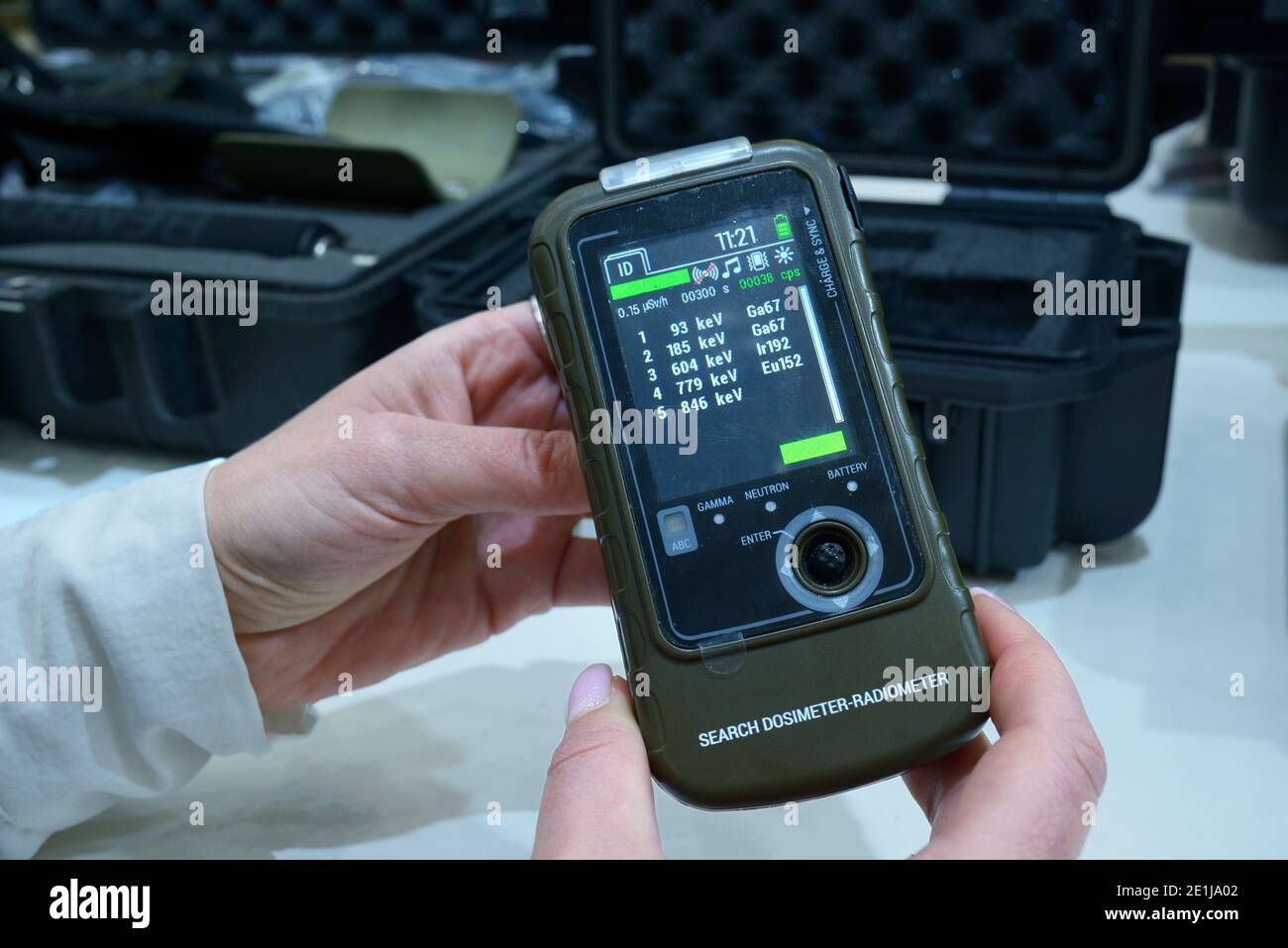 Donna mano che tiene il dosimetro-radiometro militare personale per misurare i livelli di radiazioni Foto Stock