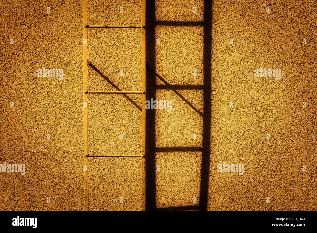La scala e la sua ombra da un edificio giallo. Foto Stock