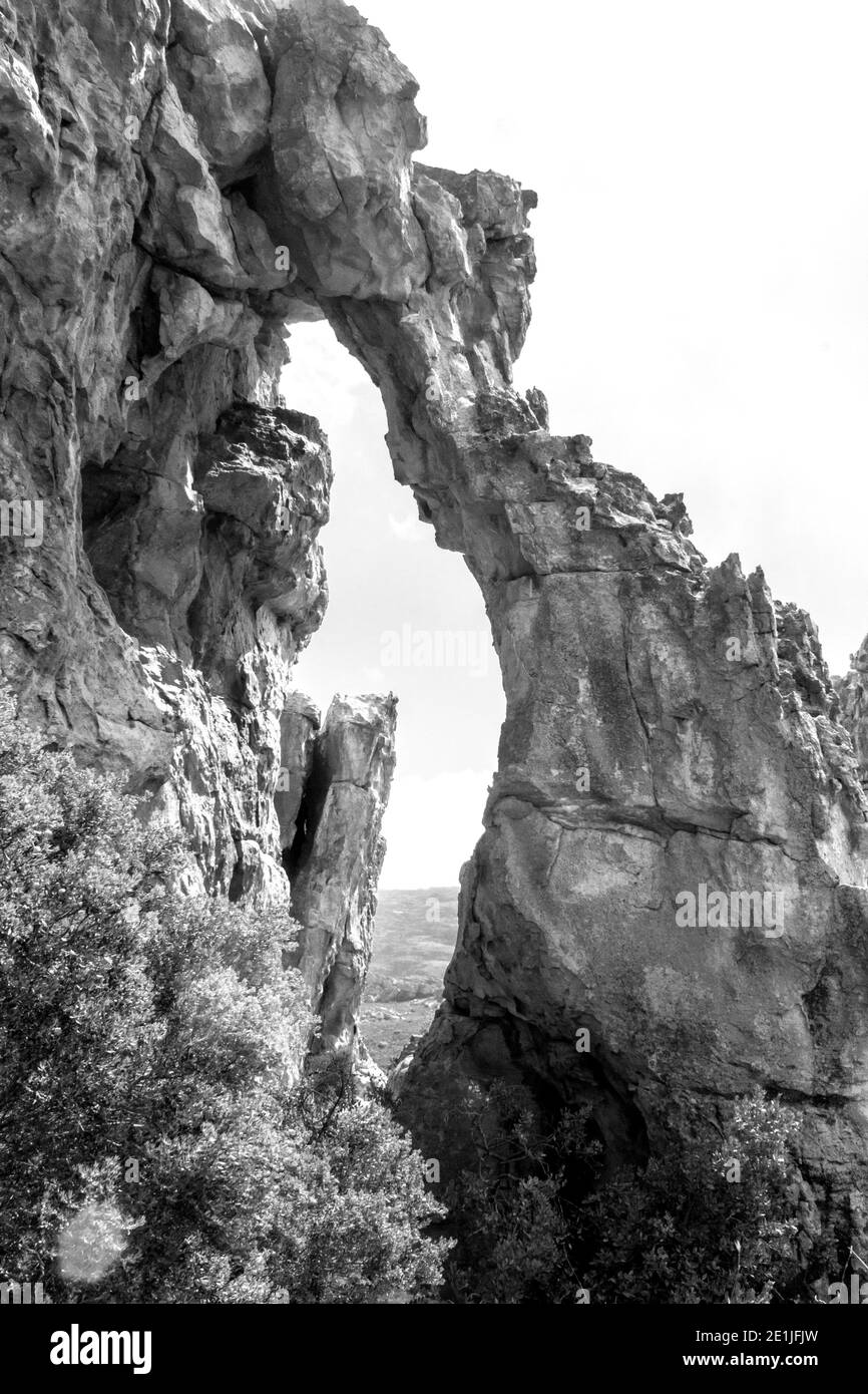 Uno stretto arco di arenaria in Monocromo, presso le grotte Stadsaal nei monti Cederberg in Sud Africa Foto Stock