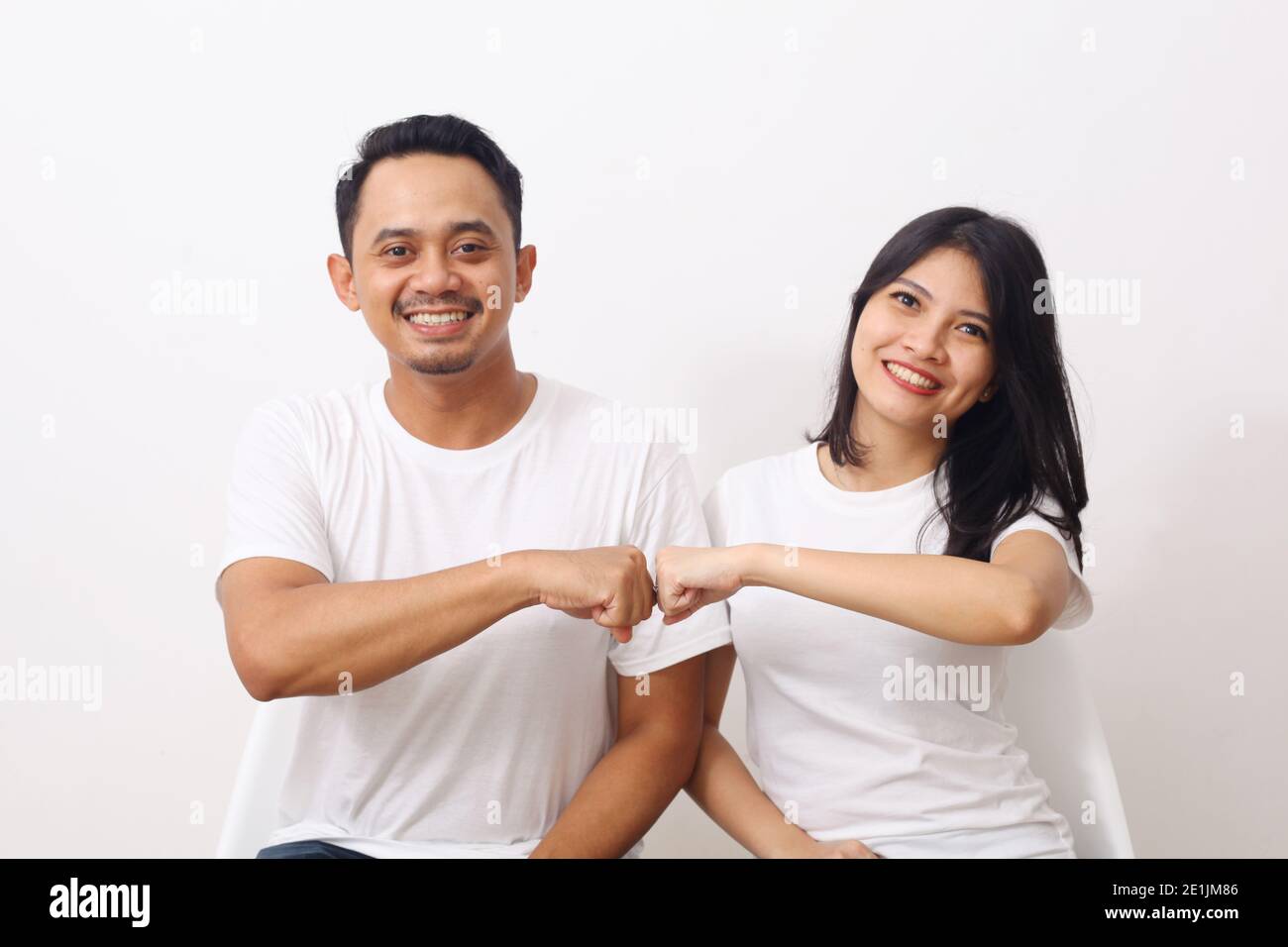 Felice coppia asiatica in camicia bianca seduta mentre fa il pugno bump. Isolato su sfondo bianco Foto Stock