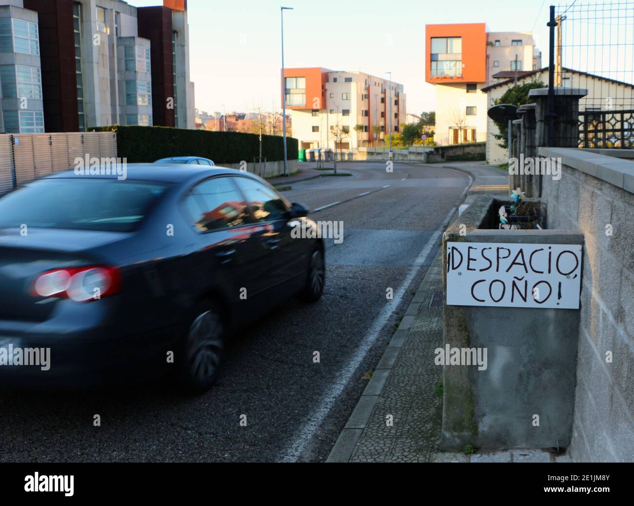 Mano stradale scritto segno in spagnolo chiedendo ai conducenti di rallentare con una macchina che passa rapidamente Santander Cantabria Spagna Foto Stock