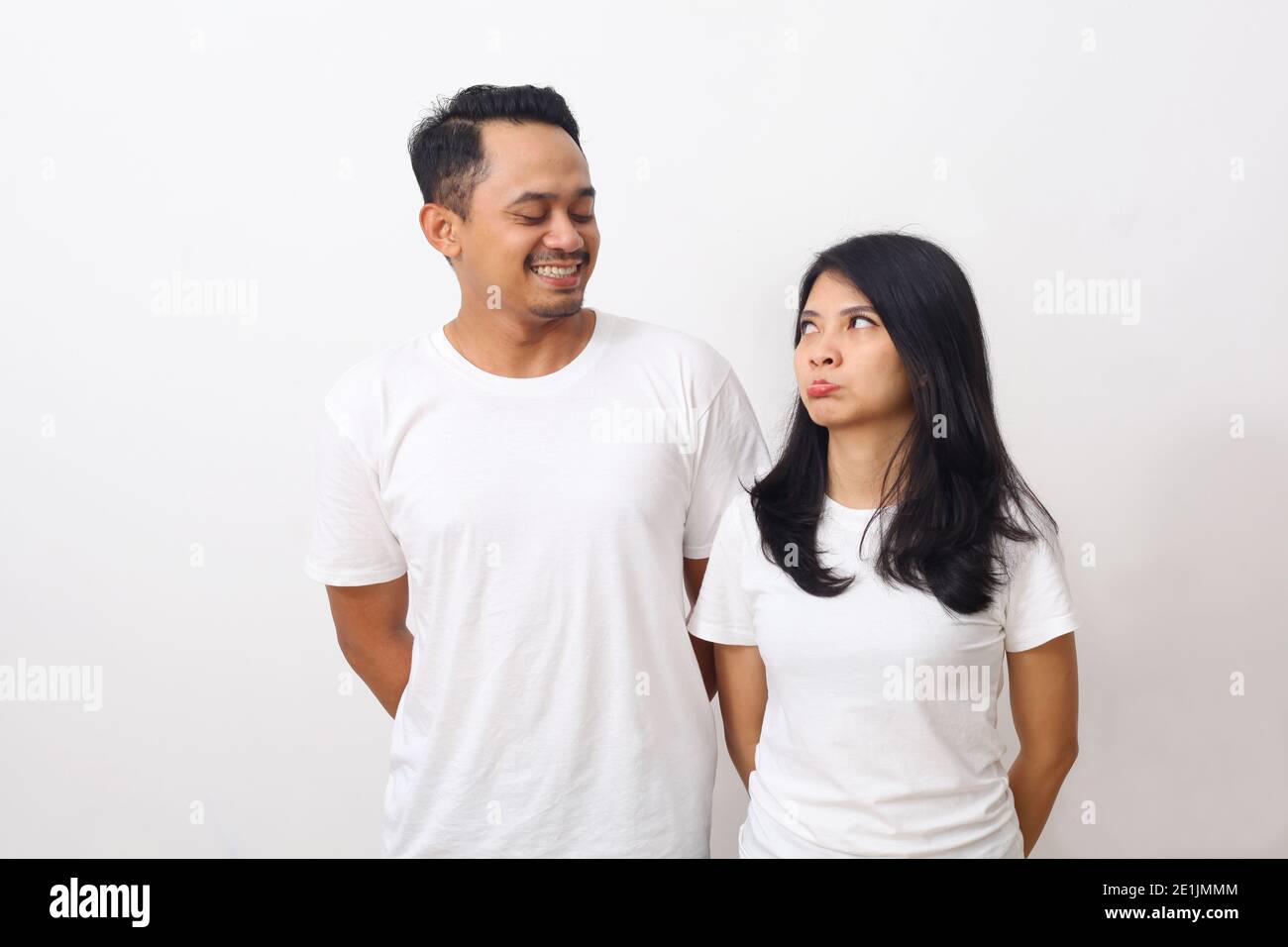 Accigliata donna carina mentre guarda il suo ragazzo. Coppia asiatica in camicia bianca isolata su sfondo bianco con copyspace Foto Stock