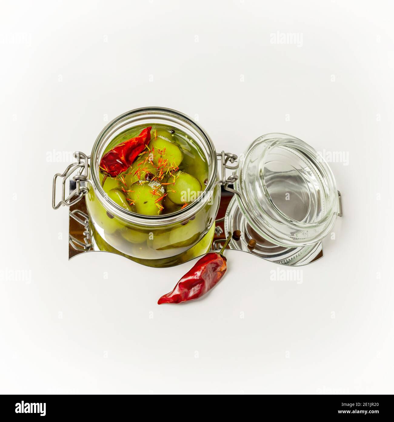 Cetrioli sottaceto con spezie e pepe in un vaso di vetro aperto su sfondo bianco. Verdure fermentate. Conservazione di cibo. Orientamento quadrato Foto Stock