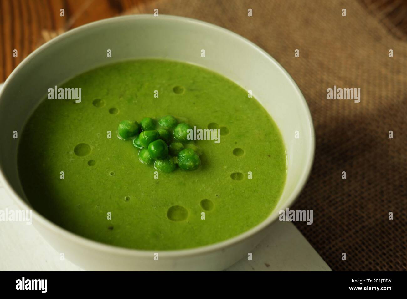 primo piano di zuppa di piselli verdi nel recipiente sulla rustuc tavolo di legno Foto Stock