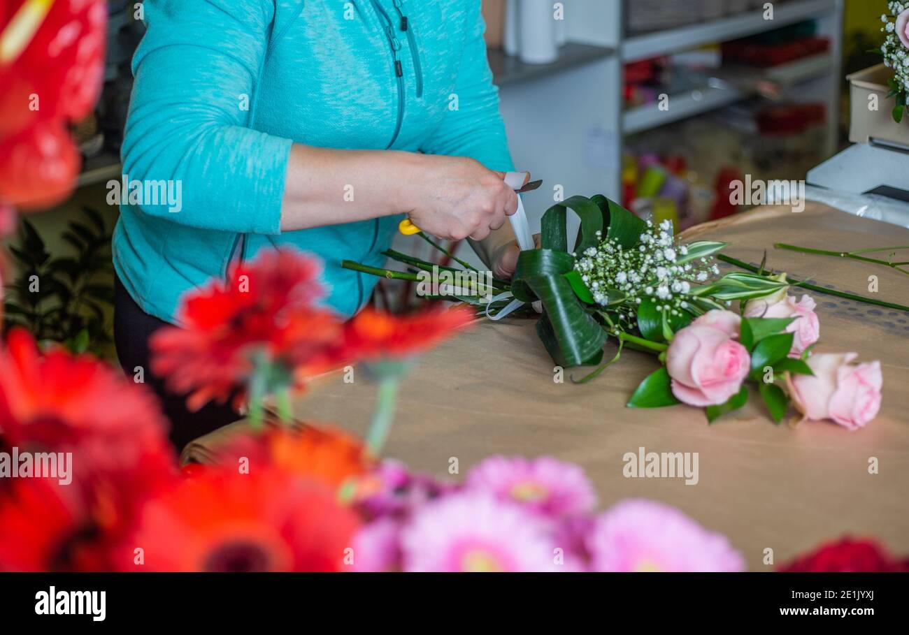 Donna fiorista lega un bouquet con rose in un fiore negozio Foto Stock