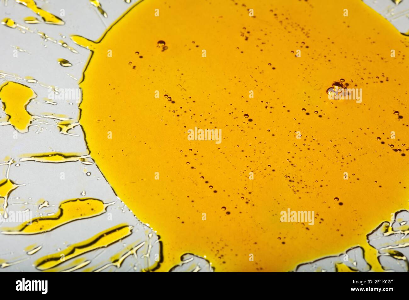Lecitina di girasole liquida viscosa gialla con bolle su vetro la forma di un girasole Foto Stock