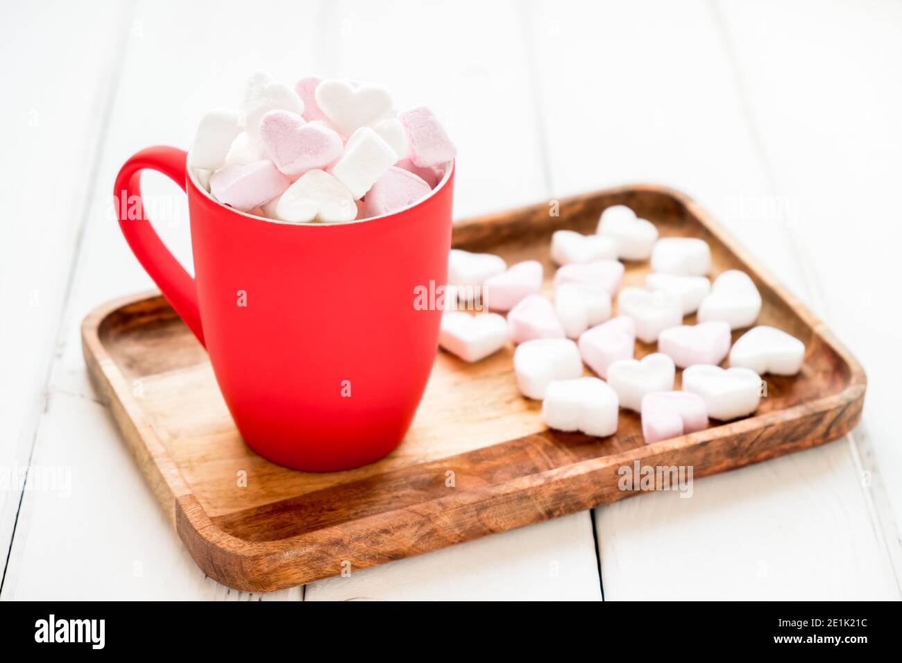 Tazza rossa di cacao caldo con marshmallows a forma di cuore sfondo bianco di legno Foto Stock