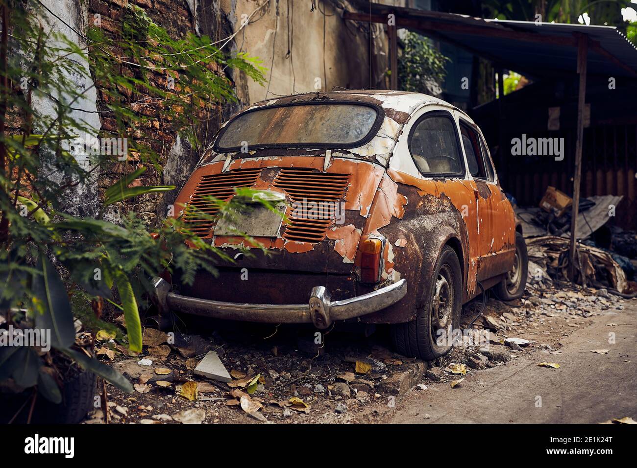 Vecchio abbandonato arrugginito bianco e arancio vintage auto relitto in una vecchia strada Foto Stock