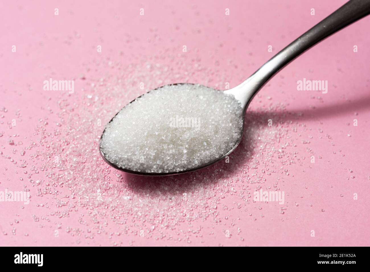Cucchiaio di zucchero su sfondo rosa Foto Stock