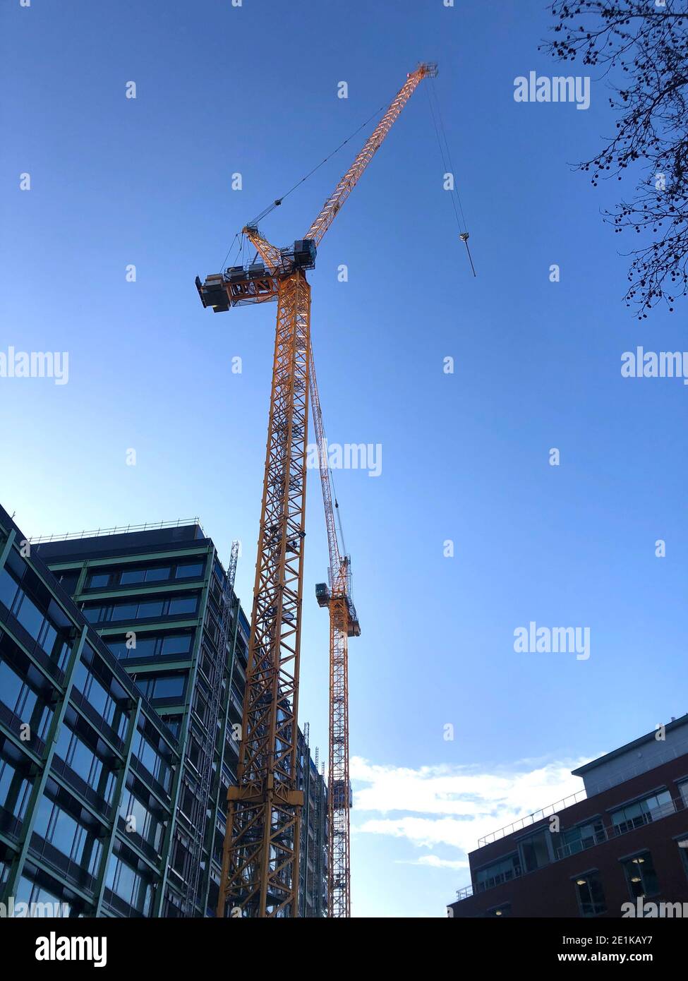 Inghilterra-Gennaio- 2021-Bristol- una vista ampia di un cantiere con due gru sollevano grandi lastre di vetro su una nuova blocco ufficio costruito Foto Stock