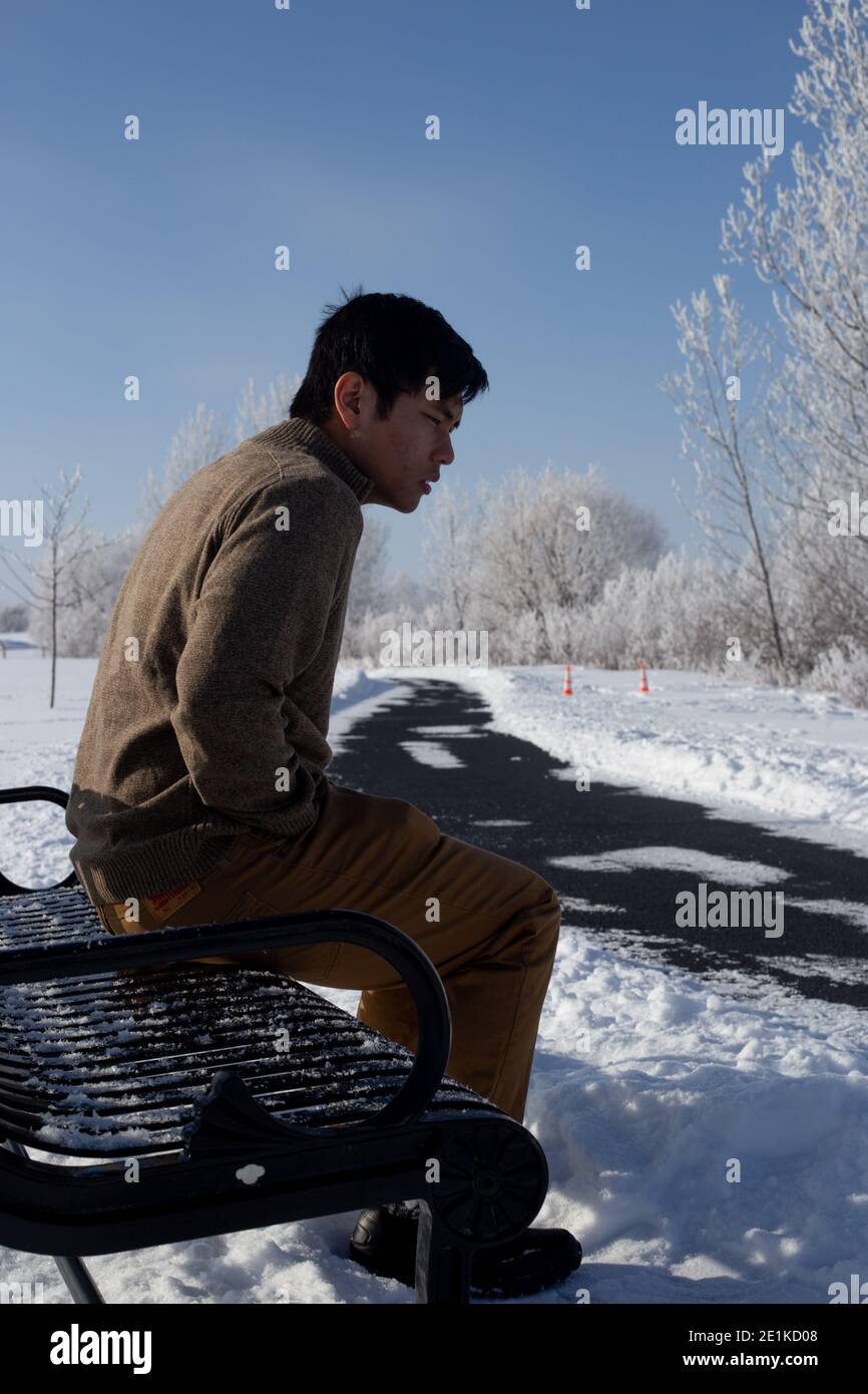 Uomo sulla panca del parco invernale Foto Stock