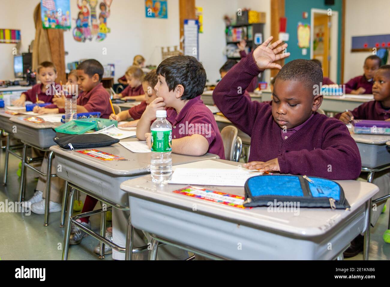 Un ragazzo alza la mano per rispondere a una domanda classe Foto Stock