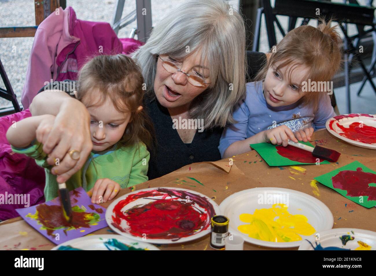 Bambini che fanno arte in una classe d'arte aiutato dagli adulti Foto Stock