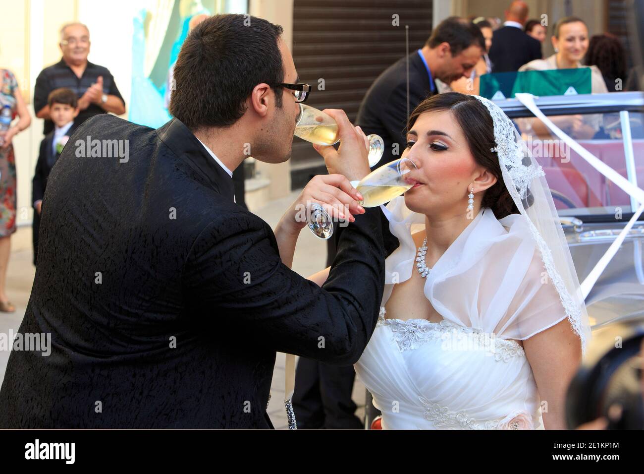 Gli sposi di recente bevono champagne fuori dalla Basilica di San Giorgio a Victoria (Gozo), Malta, dove si sono appena sposati Foto Stock