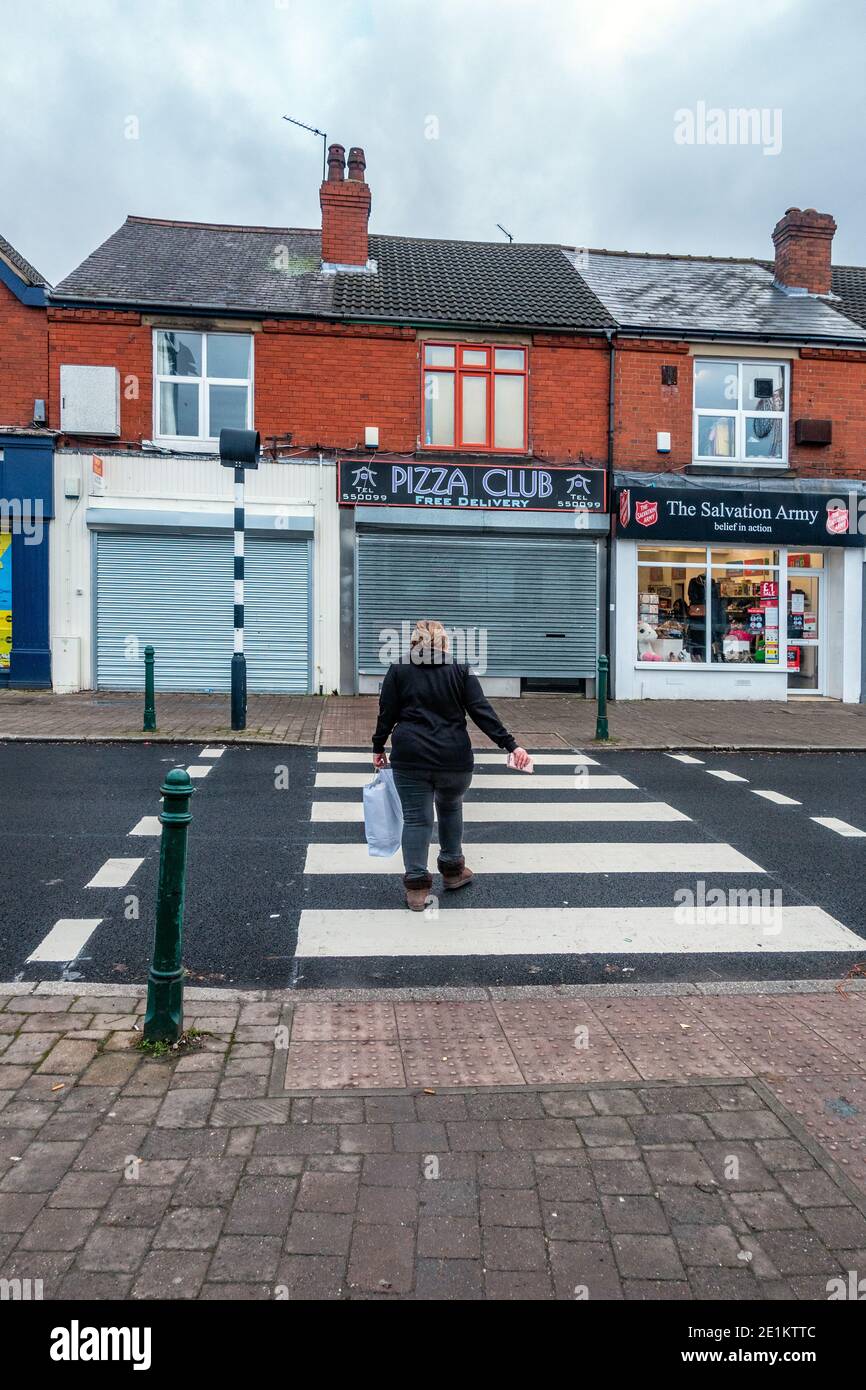 Persona che cammina via su una strada che attraversa la città Foto Stock