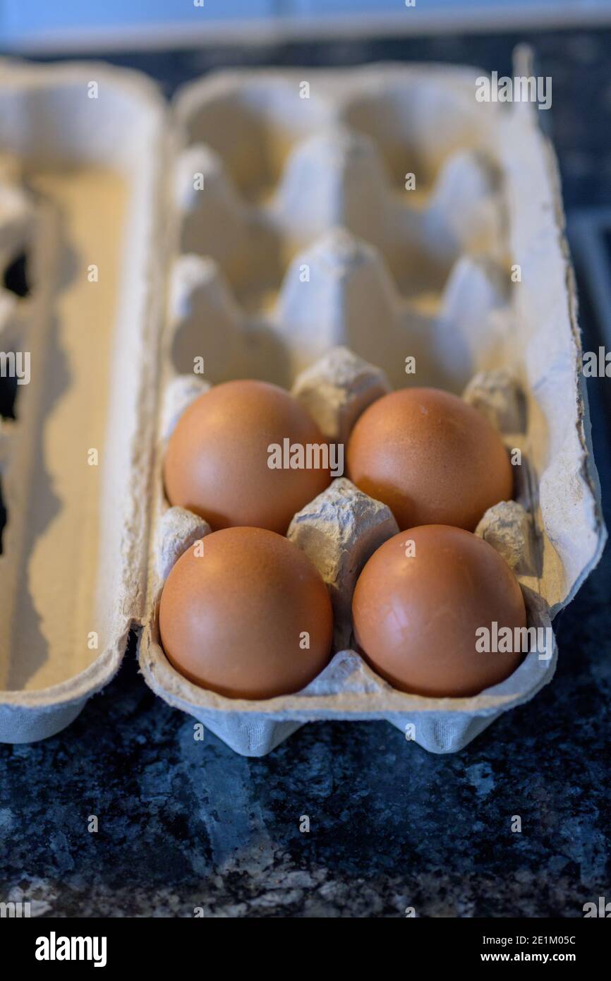 Confezione di cartone per la vendita al dettaglio con quattro uova fresche di galline marroni in una vista ravvicinata ad angolo elevato Foto Stock