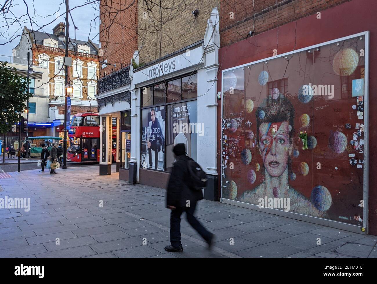 06 gennaio 2021, Regno Unito, Londra: Un uomo passa davanti al monumento a David Bowie dell'artista australiano James Cochran (Jimmy C) nell'area di Brixton, proprio di fronte alla stazione della metropolitana di Tunstall Place. Dopo la morte di Bowie il 10 gennaio 2016, centinaia di fan si sono riuniti spontaneamente a Tunstall Place per cantare le sue canzoni. Il memoriale divenne un luogo di pellegrinaggio, con i lutto che posavano fiori e foto. Poiché il dipinto era stato disseminato di messaggi scritti a mano, è stato riverniciato nel 2016. (A dpa Extra - quinto anniversario della morte di Bowie probabilmente senza tifosi in lutto a Brixton) Foto: Philip Dethlef Foto Stock