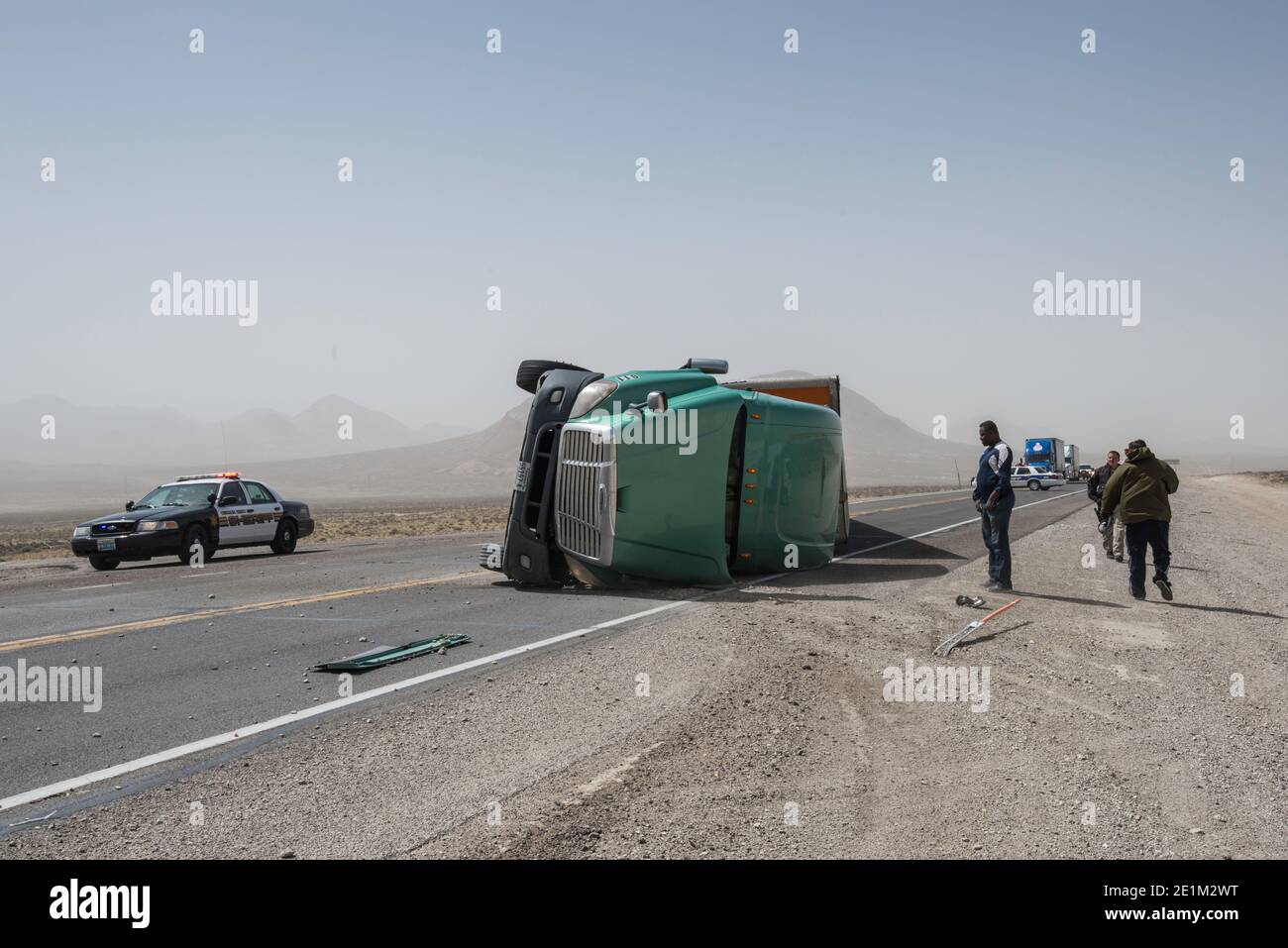 Il camion a 18 ruote rovesciato dalla forza dell'uragano si avvolge in tempesta di polvere sulla strada vicino a Tonopah, Nevada, USA Foto Stock