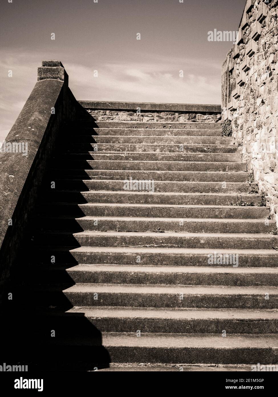 I gradini conducono a una struttura storica sotto il cielo luminoso con ombre e texture drammatiche evidenziate, la Francia Foto Stock