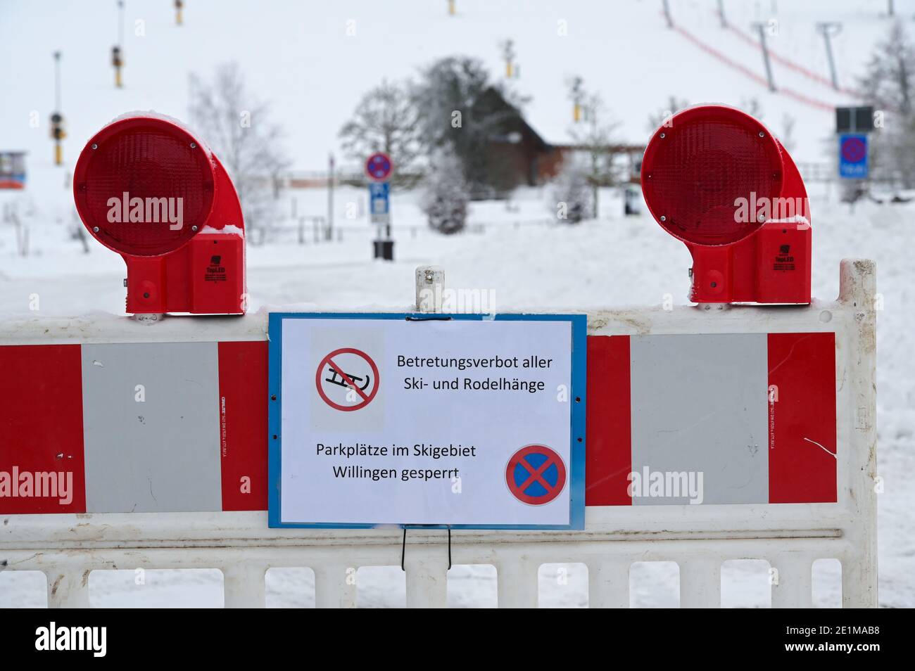 08 gennaio 2021, Hessen, Willingen: Un cartello con la scritta "Betretungsverbot aller Ski- und Rodelhänge Parkplätze im Skigebiet Willingen gesperrt" è apposto su una barriera di fronte ad un parcheggio, alla funivia e alle piste da sci. Nella località di sport invernali, il divieto di accedere alle piste da sci e alle piste per slittino è in vigore da questo venerdì a causa della pandemia di Corona. Il divieto è stato innescato dalla situazione lo scorso fine settimana: Dopo che la regione degli sport invernali di Winterberg, nella vicina Renania settentrionale-Vestfalia, aveva chiuso piste e parcheggi, migliaia di escursionisti si erano riversati nel nord dell'Assia. P. Foto Stock