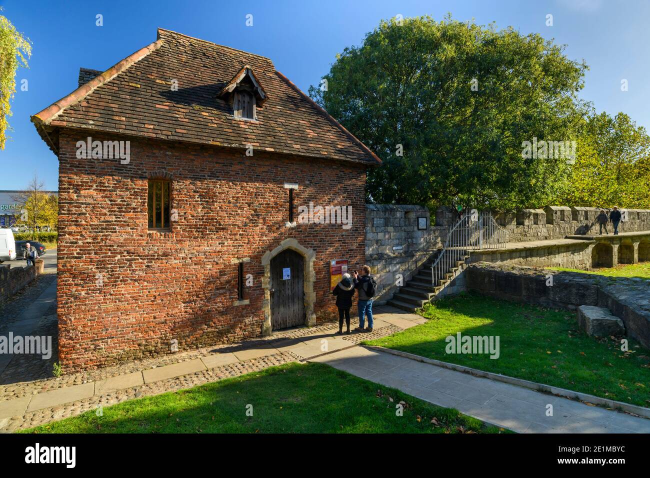 I turisti si levano in piedi e scattano foto della Torre Rossa C15 e una passeggiata di coppia sulle mura medievali dei bar illuminate dal sole - attrazioni storiche a York, North Yorkshire, Inghilterra, Regno Unito. Foto Stock