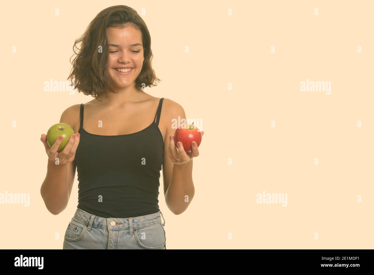 Giovane ragazza giovane felice caucasica adolescente sorridente mentre sceglie tra rosso e mela verde Foto Stock